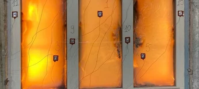 Фрагмент светопрозрачного фасада в огневой печи лаборатории: стекло раскалено, на профилях закреплены термопары